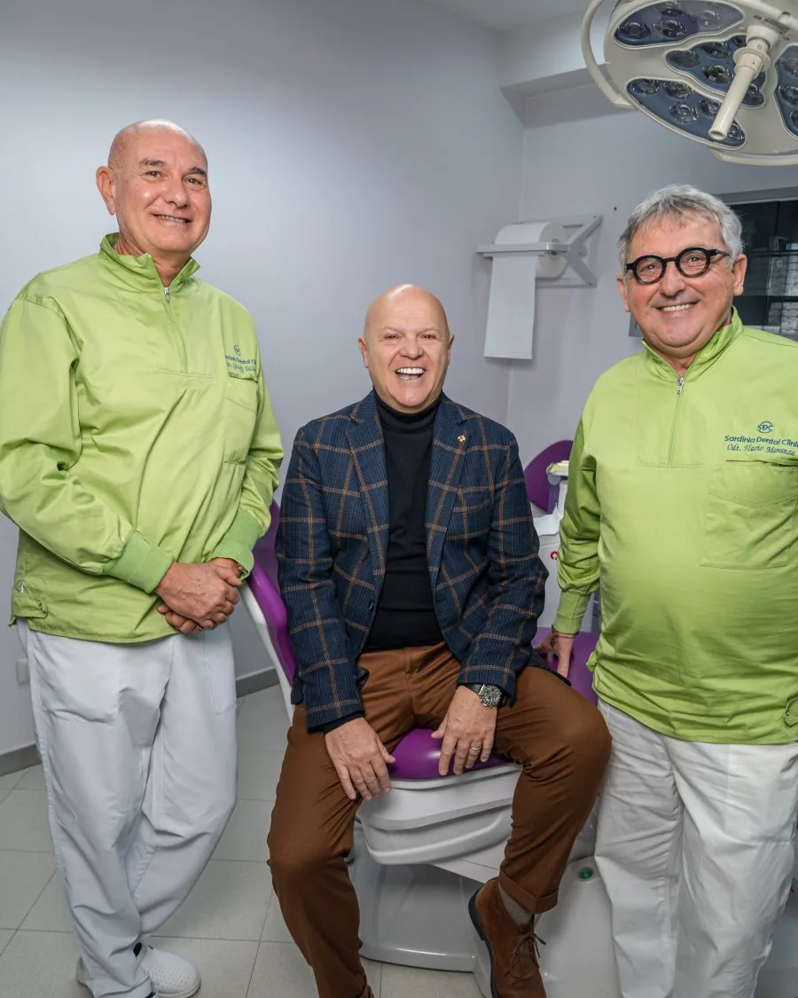 I dottori Manunza e Valdarchi con un paziente sorridente nella clinica di Olbia dopo i denti fissi su impianti